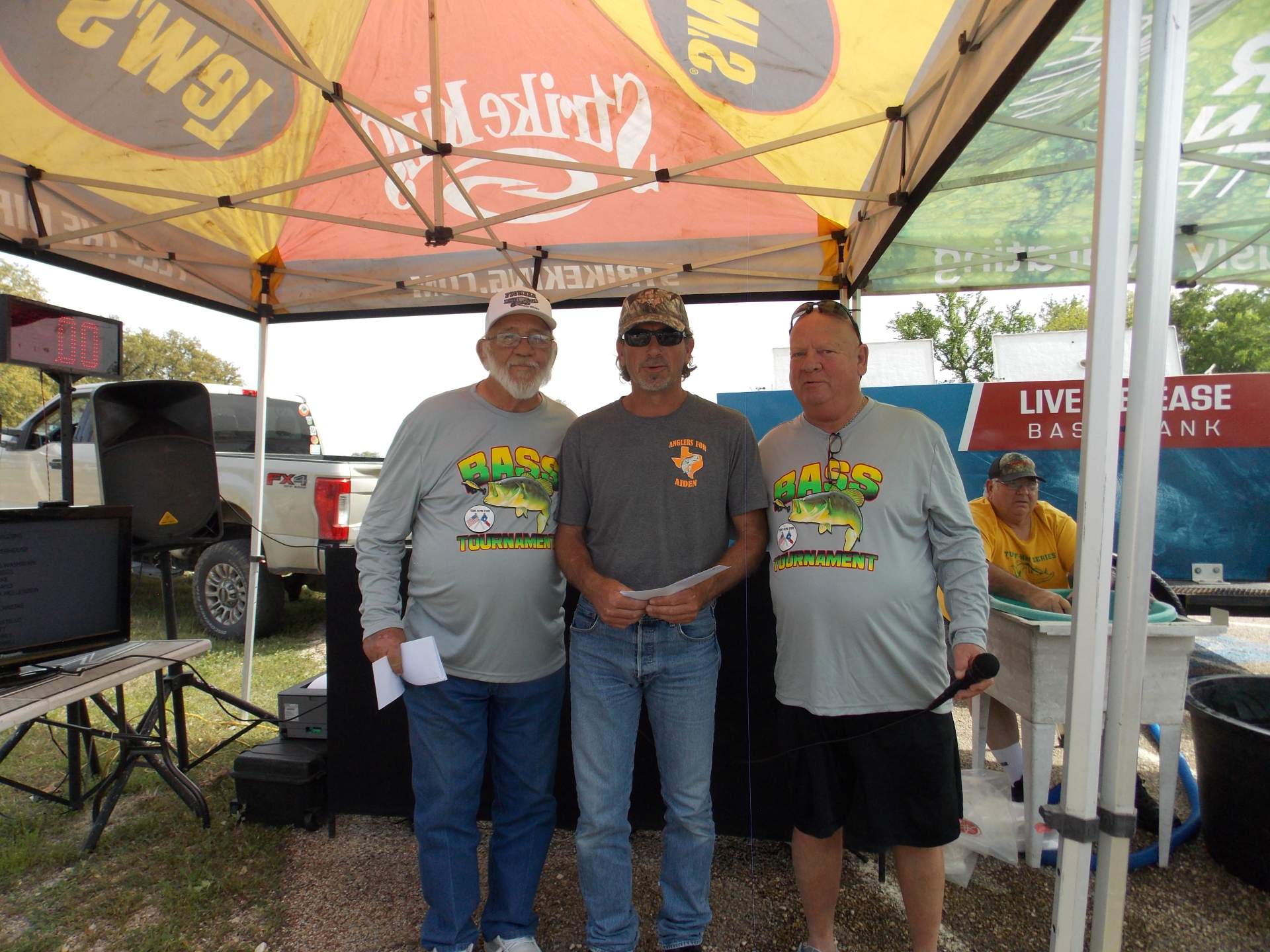 Three tournament winners standing under a canopy