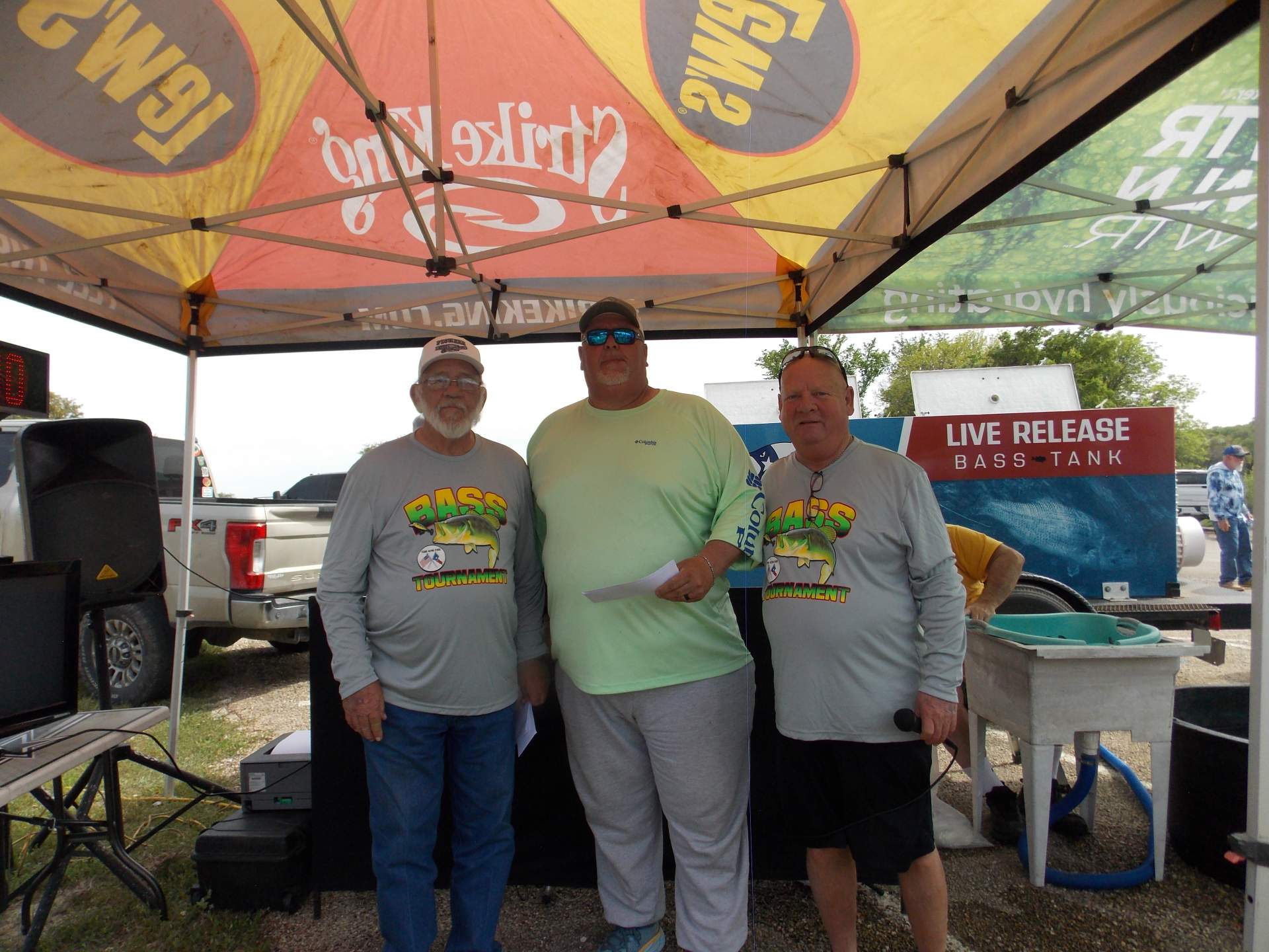 Three tournament winners standing under a canopy